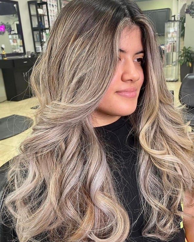 Clienta de D'Vicente Beauty Salon sonriendo con balayage rubio y ondas